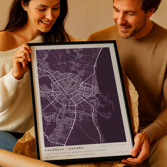 Pareja feliz abriendo un regalo personalizado: un póster enmarcado con el mapa de la ciudad donde empezó su historia de amor. El diseño muestra calles detalladas, una frase emotiva y sus nombres, creando un recuerdo único. Regalo ideal para parejas que quieren celebrar un lugar especial con un detalle original y de alta calidad.